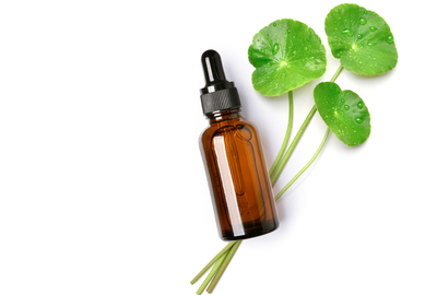 Amber dropper bottle with Centella Asiatica (cica) leaves on a white background, symbolizing natural skincare ingredients