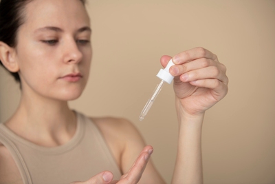 Woman applying glycolic acid serum with a dropper, focusing on skincare routine and exfoliation