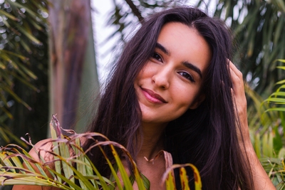 Young woman with glowing sensitive skin smiling outdoors in a natural setting.