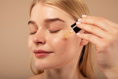 Young woman applying serum to her face as part of skincare for different types of acne.