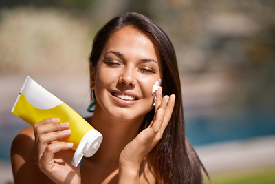 Woman applying zinc oxide mineral sunscreen on face for UV protection